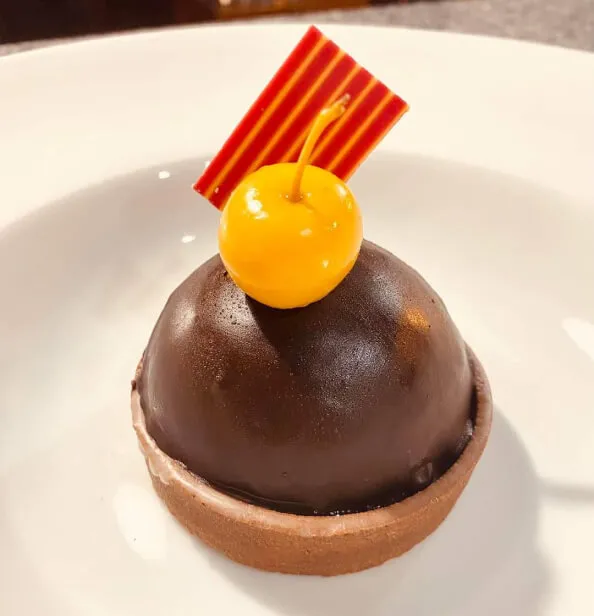 Una tarta de chocolate decorado con una guinda y una chocolatina.